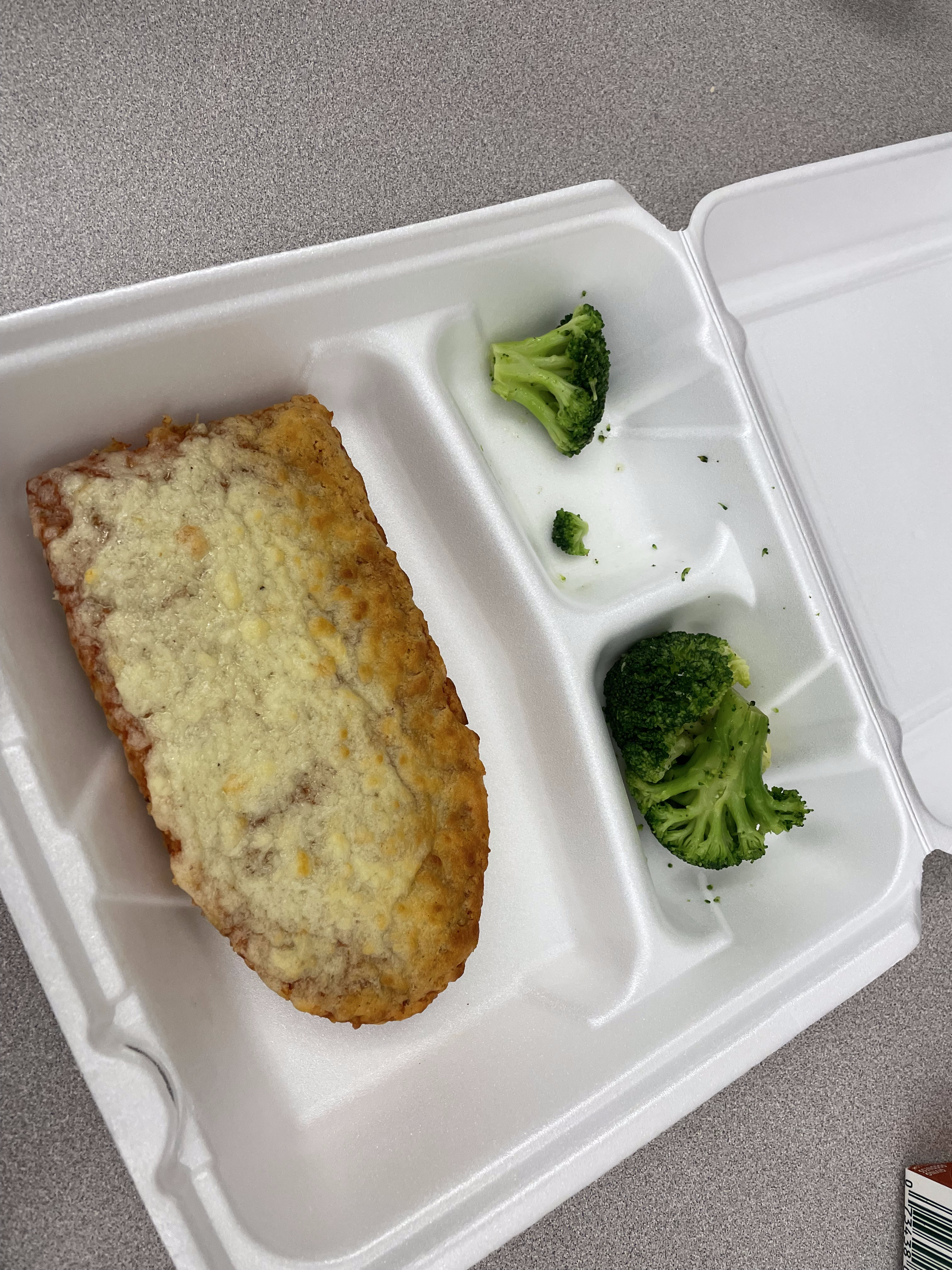 bad looking pizza with small pieces of broccoli for the school lunch